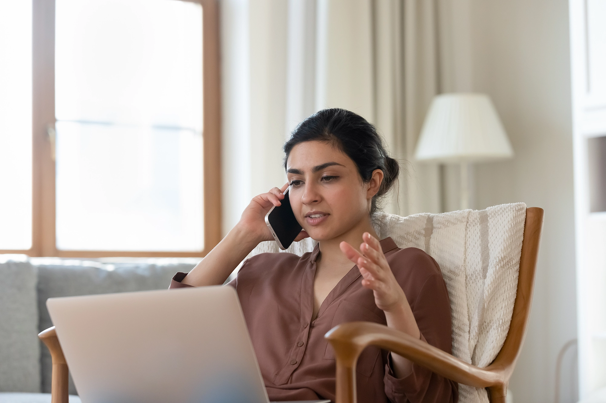 A woman reporting abuse over the phone while looking at a laptop